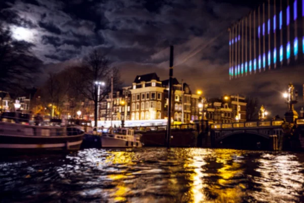 Nacht verlichting reflecties in Amsterdam kanalen verplaatsen cruise boot. Wazig abstracte foto als achtergrond. — Stockfoto