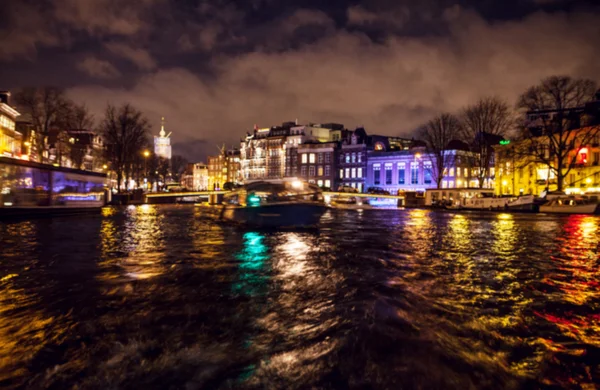 Nacht verlichting reflecties in Amsterdam kanalen verplaatsen cruise boot. Wazig abstracte foto als achtergrond. — Stockfoto