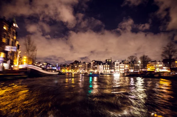 Night lighting reflections in Amsterdam channels from moving cruise boat. Blurred abstract photo as background. — Stock Photo, Image