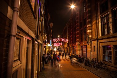 Night streets of Amsterdam with blurred silhouettes of passersby.
