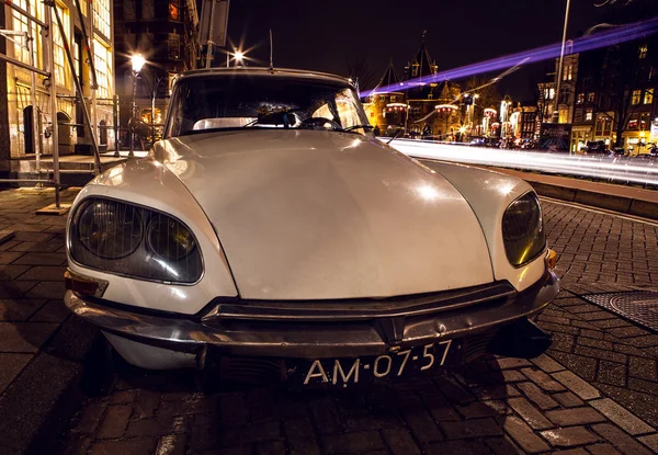 AMSTERDAM, NETHERLANDS - JANUARY 5, 2016: Vintage white car parked in center of Amsterdam at night time. January 5, 2016 in Amsterdam - Netherland. — Stockfoto