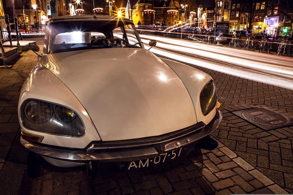 AMSTERDAM, NETHERLANDS - JANUARY 5, 2016: Vintage white car parked in center of Amsterdam at night time. January 5, 2016 in Amsterdam - Netherland. — Stockfoto