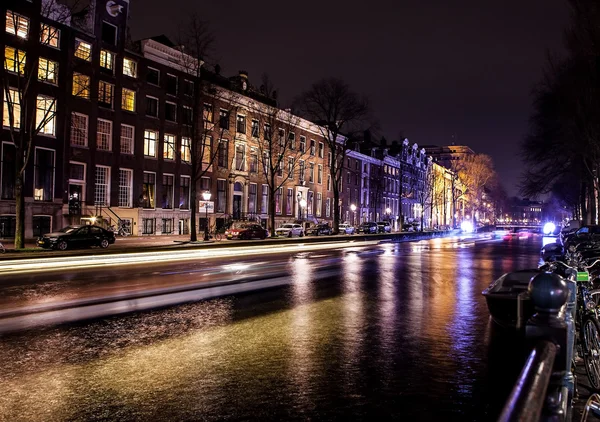 Cruise boot met onscherpte licht bewegen op nacht grachten van Amsterdam. — Stockfoto