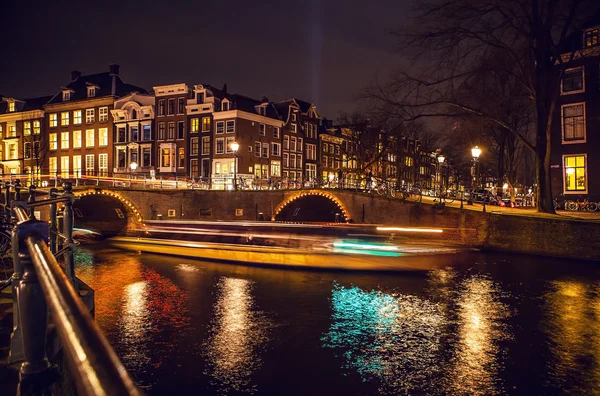 Cruise boot met onscherpte licht bewegen op nacht grachten van Amsterdam. — Stockfoto