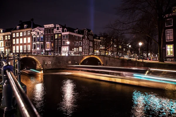 Cruise boot met onscherpte licht bewegen op nacht grachten van Amsterdam. — Stockfoto