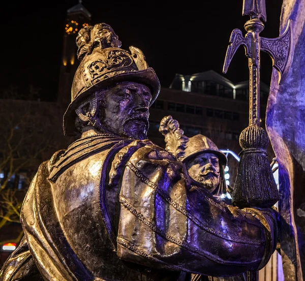 AMSTERDAM, NETHERLANDS - DECEMBER 19, 2015: Bronze figures of soldiers on central square of city lit with street light at night on December 19, 2015 in Amsterdam - Netherland. — Stock Photo, Image