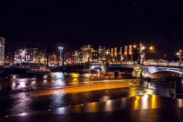 Bateau de croisière avec lumière floue se déplaçant sur les canaux de nuit d'Amsterdam . — Photo