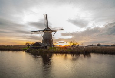 Hollanda, Kinderdijk 'te gün batımında yel değirmenleri ve su kanalları.