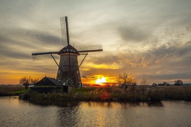 Hollanda, Kinderdijk 'te gün batımında yel değirmenleri ve su kanalları.
