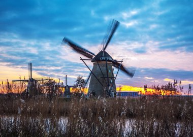Hollanda, Kinderdijk 'te gün batımında yel değirmenleri ve su kanalları.