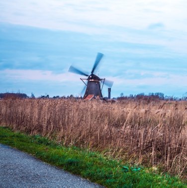 Hollanda, Kinderdijk 'te gün batımında yel değirmenleri ve su kanalları.