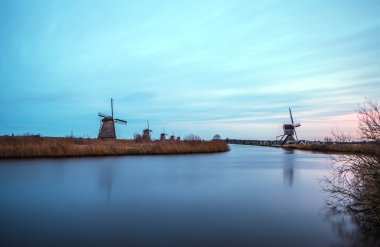 Hollanda, Kinderdijk 'te gün batımında yel değirmenleri ve su kanalları.