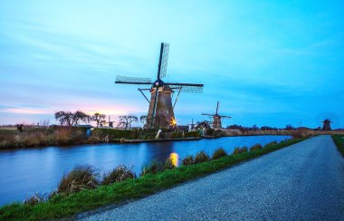 Hollanda, Kinderdijk 'te gün batımında yel değirmenleri ve su kanalları.