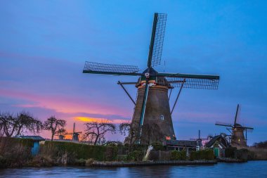 Hollanda, Kinderdijk 'te gün batımında yel değirmenleri ve su kanalları.