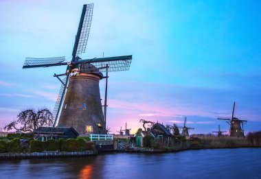 Hollanda, Kinderdijk 'te gün batımında yel değirmenleri ve su kanalları.