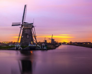Hollanda, Kinderdijk 'te gün batımında yel değirmenleri ve su kanalları.