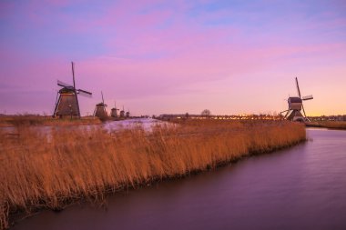 Hollanda, Kinderdijk 'te gün batımında yel değirmenleri ve su kanalları.