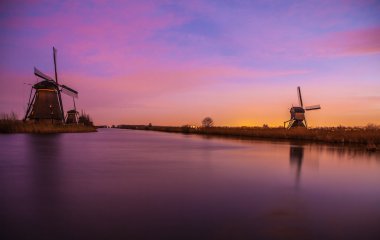 Hollanda, Kinderdijk 'te gün batımında yel değirmenleri ve su kanalları.