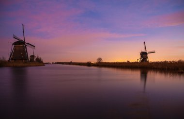 Hollanda, Kinderdijk 'te gün batımında yel değirmenleri ve su kanalları.