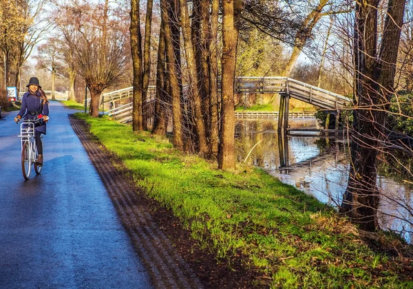 Young girl goes by bicycle near river channel. — Stock Photo, Image