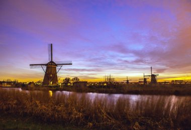 Hollanda, Kinderdijk 'te gün batımında yel değirmenleri ve su kanalları.
