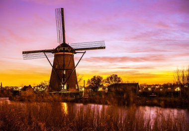 Hollanda, Kinderdijk 'te gün batımında yel değirmenleri ve su kanalları.