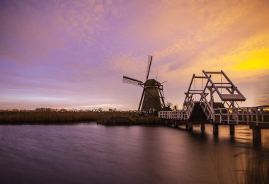 Hollanda, Kinderdijk 'te gün batımında yel değirmenleri ve su kanalları.