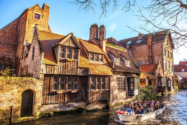 Rugge, België - 17 januari 2016: Vervoer boot met toeristen die op oude gebouw van de middeleeuwse stad op 17 januari, 2016 in Brugge - België uitzien. — Stockfoto