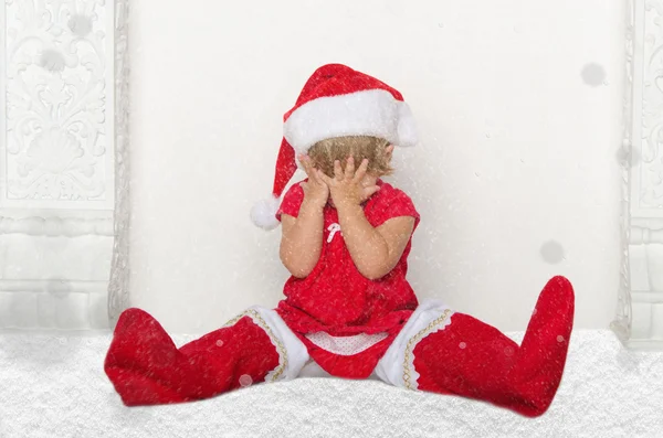 Małe dziecko w garnitur Santa, siedząc na podłodze ze śniegu — Zdjęcie stockowe