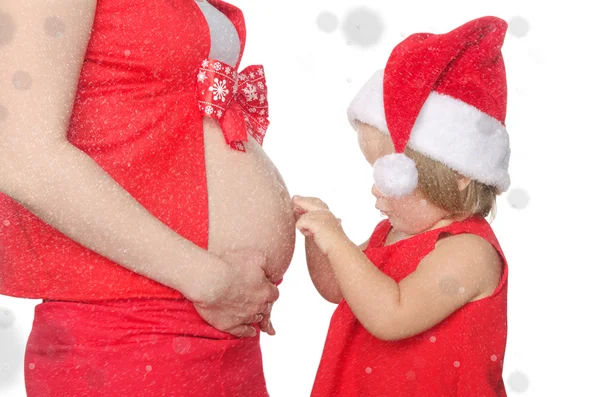 Ребенок и беременная женщина живот на Рождество, снежинки — стоковое фото