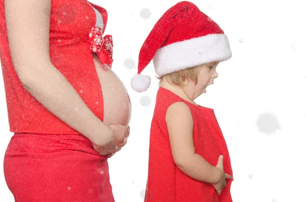 Malé dítě a těhotná žena břicho na Vánoce, sněhové vločky — Stock fotografie