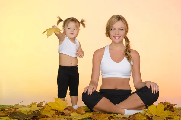 Beautiful woman and child doing yoga in fall — Stock Photo, Image