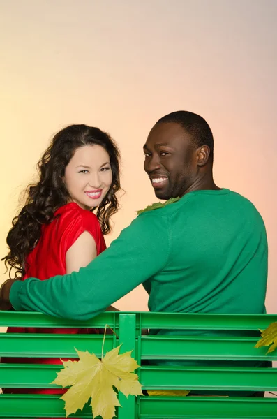 Fekete férfi és ázsiai nő a padon, őszi — Stock Fotó