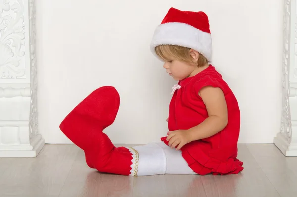 Chica en traje de Santa mira a sus pies — Foto de Stock