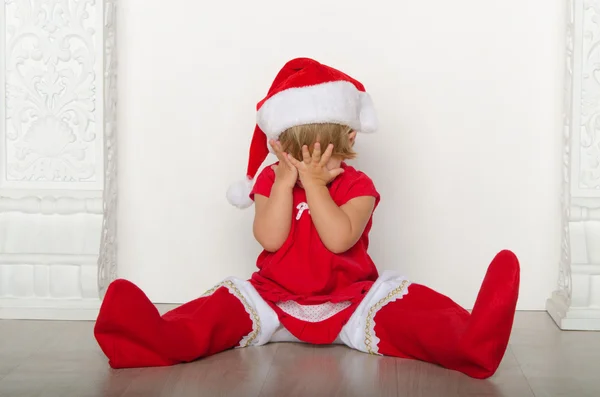 Dívka v kostýmu Santa skryje obličej — Stock fotografie