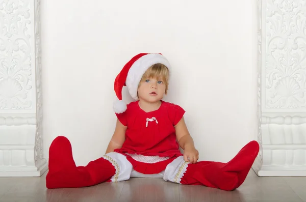 Meisje in kostuum van Santa Claus zittend op de vloer — Stockfoto