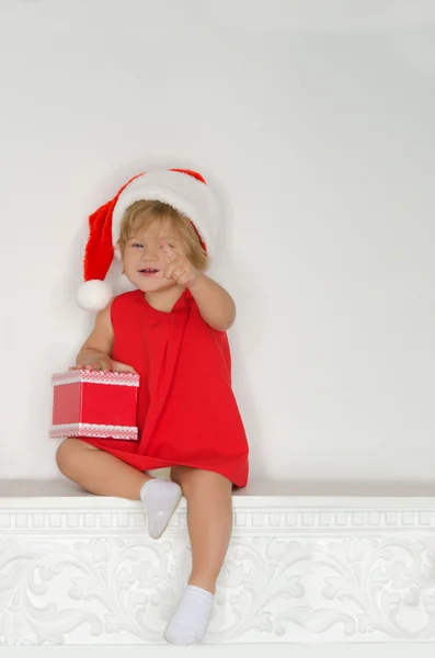Meisje in kostuum van Santa zittend op open haard — Stockfoto