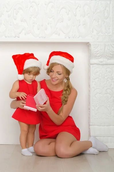 Vrouw met een kind in kostuums Santa kijken gift — Stockfoto