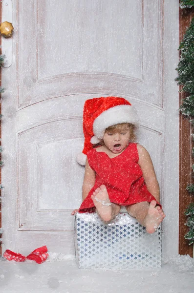 Child dressed as Santa is sitting on box and sings — Stock Photo, Image