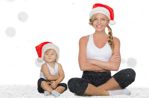 Mom and daughter doing yoga in Christmas hats — Stock Photo, Image