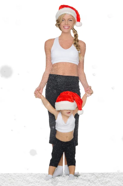 Žena s dítětem v sněhová v Santa klobouky — Stock fotografie