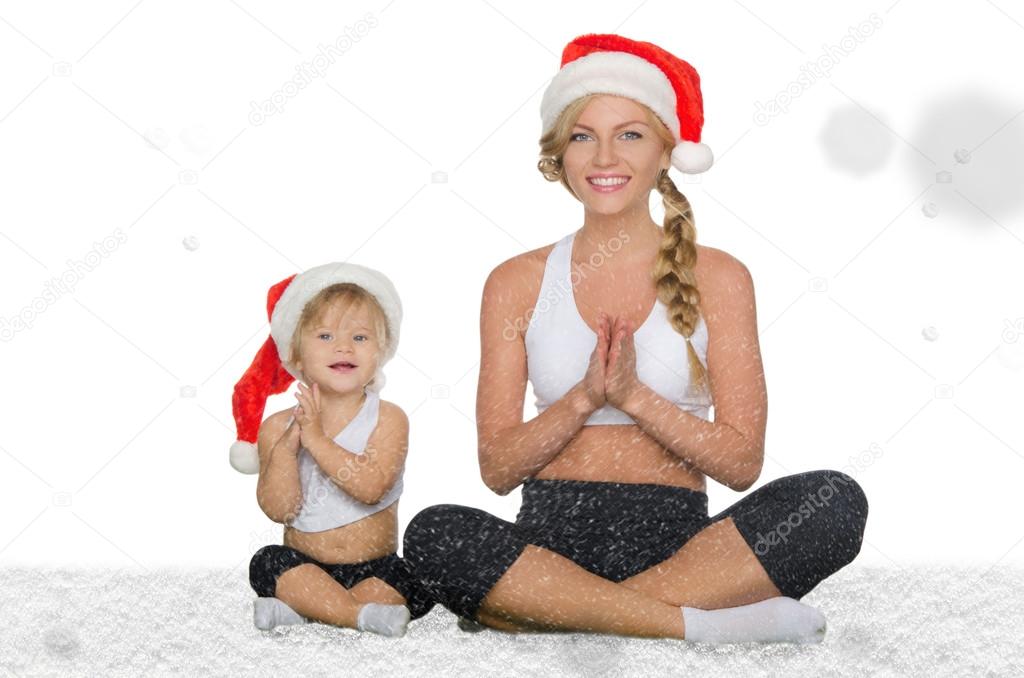 Woman with child doing yoga under falling snow