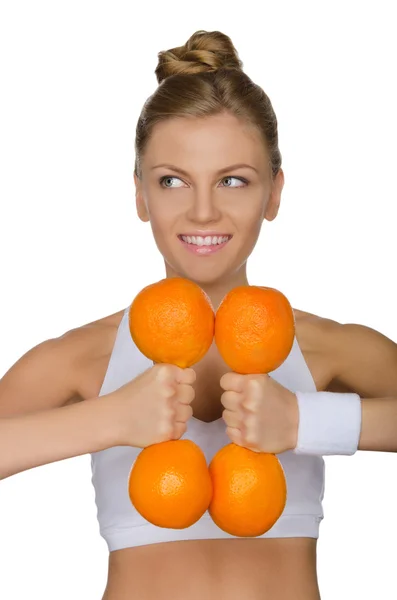 Girl and dumbbell of oranges, looks to the side — Stock Photo, Image