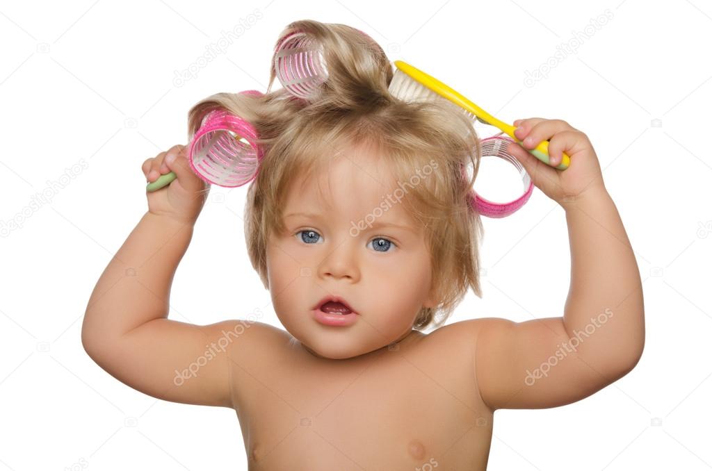 Little beautiful girl with hair curlers and comb