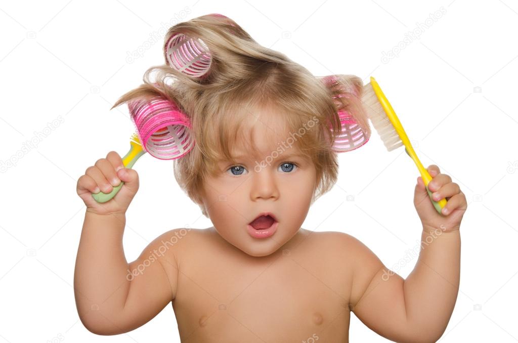 Little beautiful kid with hair curlers and comb