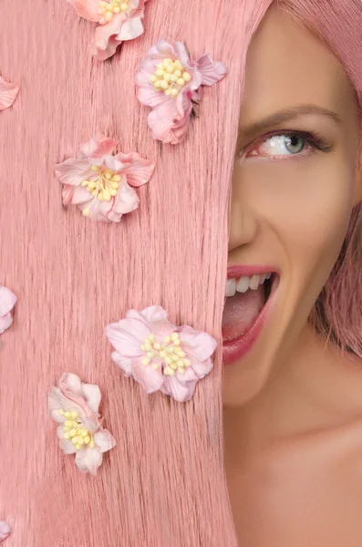 Vrouw met roze haren en bloemen op zoek naar kant — Stockfoto