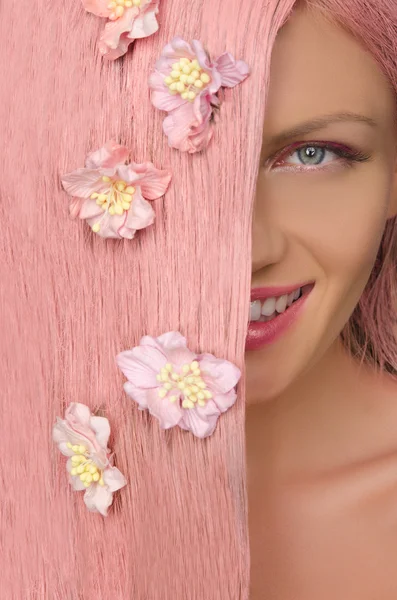 Vrouw met roze haren en bloemen camera kijken — Stockfoto