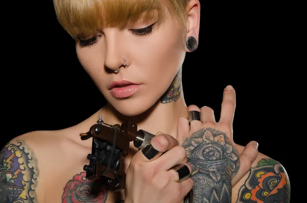 Jeune femme tatouée avec machine à tatouer Image En Vente