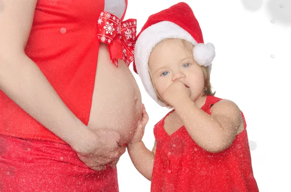 Ребенок слушает живот беременной женщины, Рождество, снежинки — стоковое фото