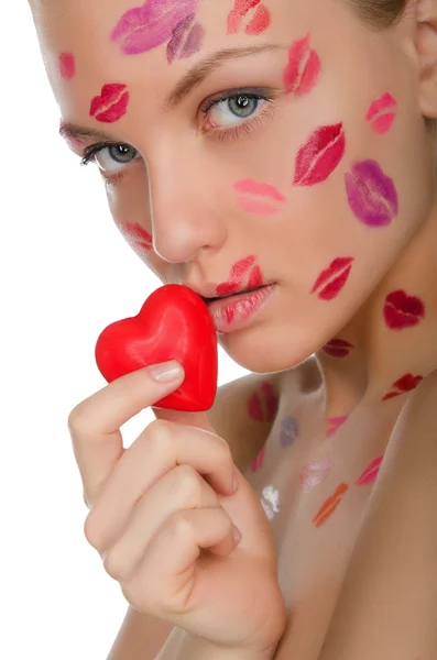 Beautiful woman with kisses on face holding heart in mouth — Stock Photo, Image